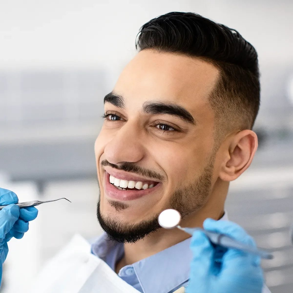 A man with a cheerful expression sits in a dentist chair, undergoing cosmetic dentistry