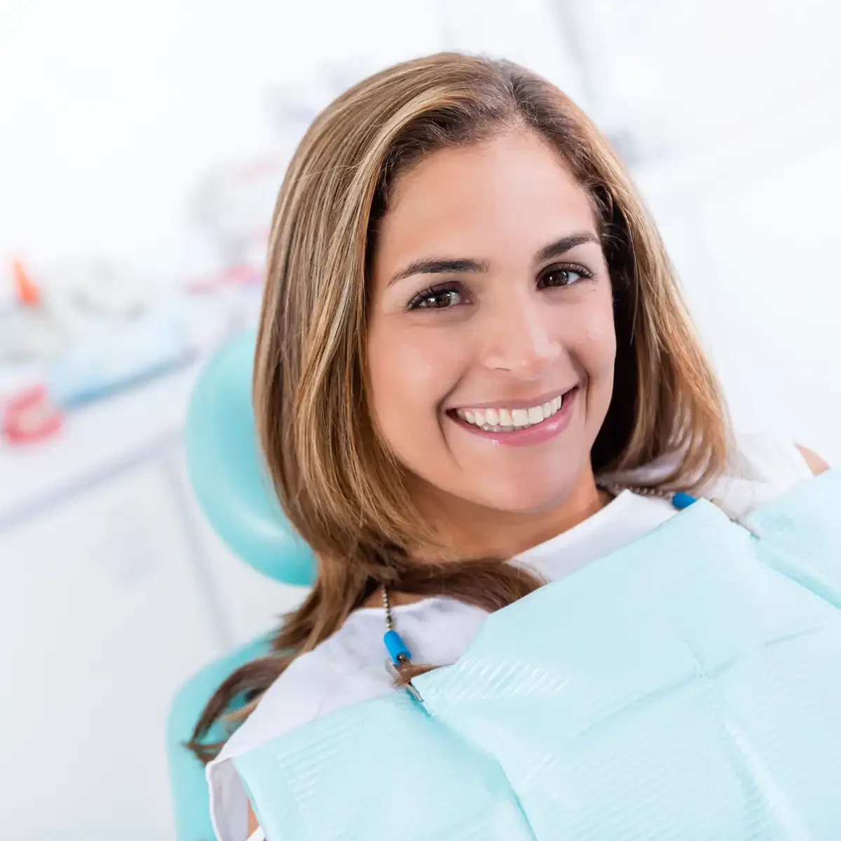 A woman smiling in a dental chair during bone grafting procedure