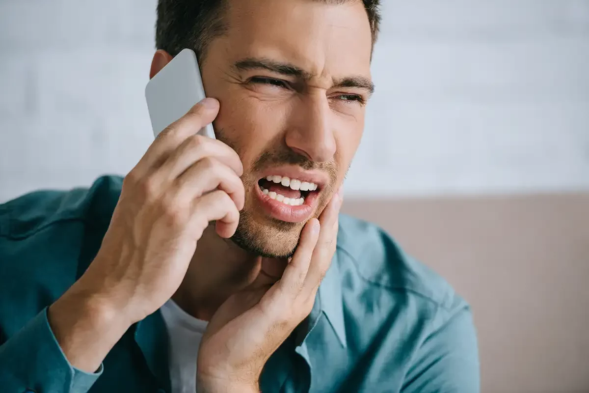 A man in a dental emergency is talking on his cell phone