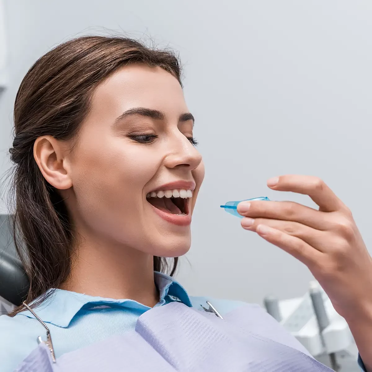 Woman smiling in dentist chair during retainer fitting