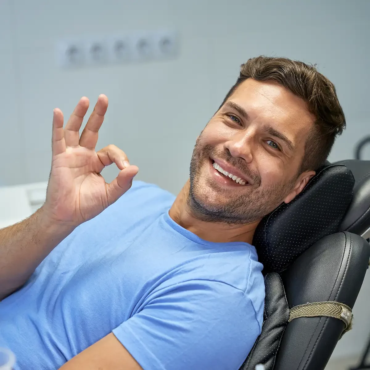 A man in a dentist chair making an okay sign, undergoing a root canal procedure