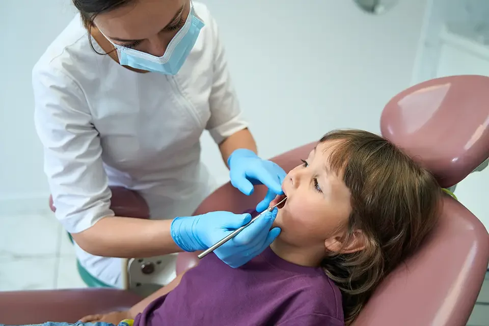 experienced-pedodontist-inspecting-teeth-of-little-girl Pediatric Thumb-Sucking: Early Signs It's Affecting Growth