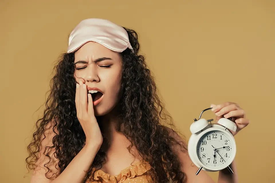 sleepy-woman-yawns-with-alarm-clock-faded-yellow Effects of Tooth Pain on Sleep