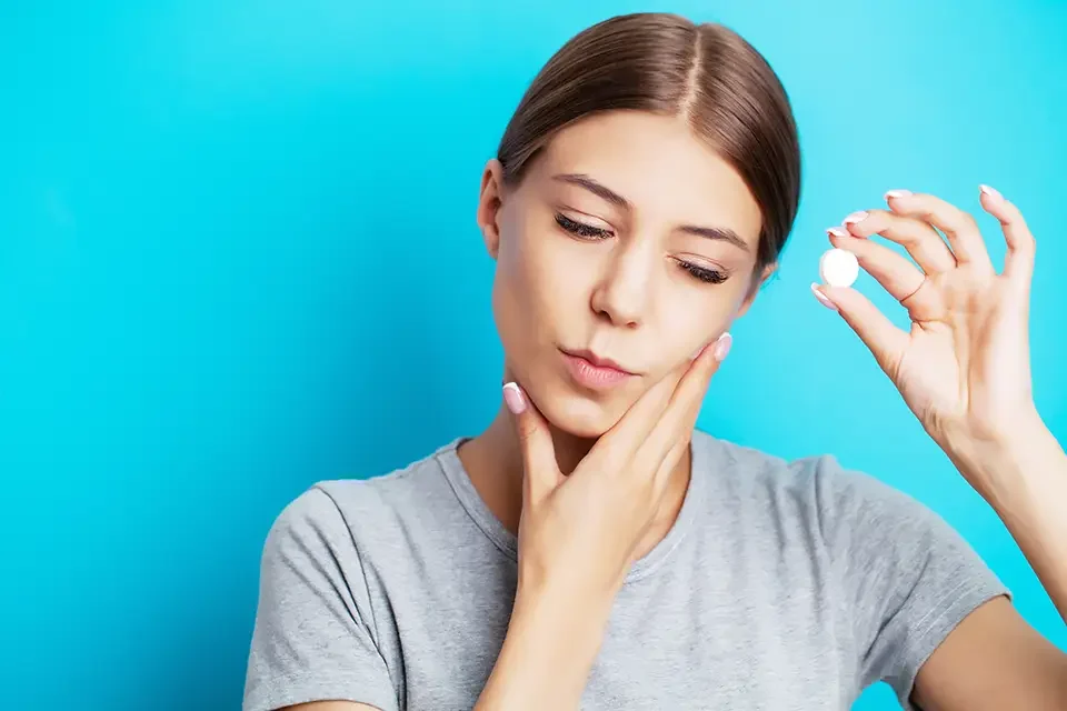 woman with toothache takes a pill When Do Wisdom Teeth Typically Erupt?